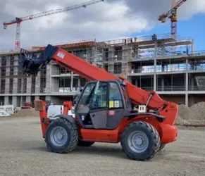 Sustainable machinery on construction sites. Red telescopic handler and cranes at an eco-friendly construction site.