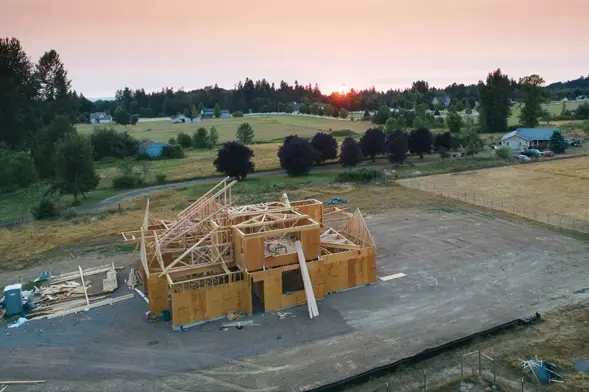 Sustainable Construction Using CleanTech Solutions. Aerial view of a wooden house under construction at sunset using sustainable building practices.