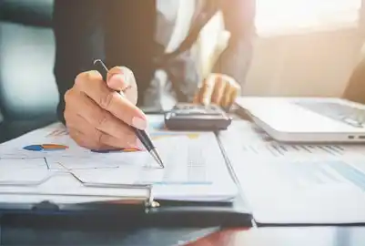 Financing Sustainable Business Growth. Business professional reviewing financial documents with charts and a calculator.