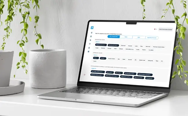 Digital platform for matching cleantech solutions with enterprise needs. Laptop displaying a cleantech solution matching platform on a white desk with green plants.
