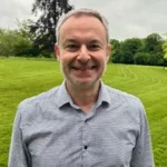 Daniel Eskenazi, Chief Marketing Officer, smiling outdoors in a green park.