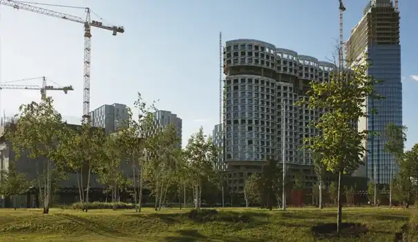 Smarter Building Management Through Sustainability. Modern high-rise buildings under construction surrounded by trees and cranes.