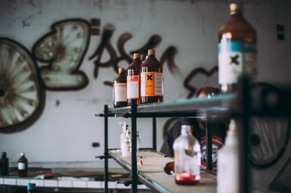 Toxic Products Requiring Careful Handling and Disposal. Bottles of toxic chemicals with warning labels on metal shelves in an abandoned space.