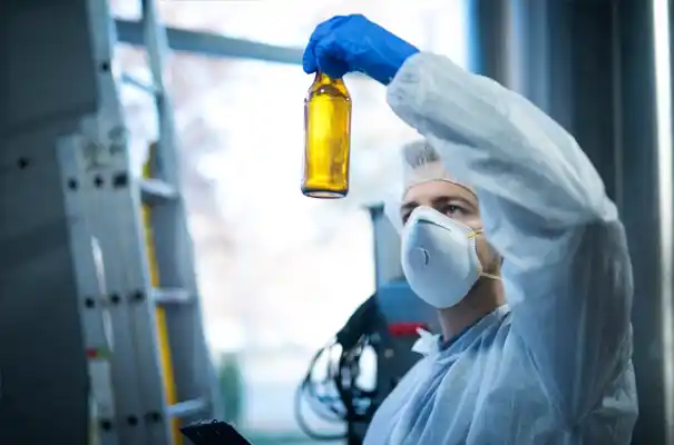 Managing Toxic Substances with Safer Solutions. Technician in protective gear examining a chemical bottle in a lab environment.