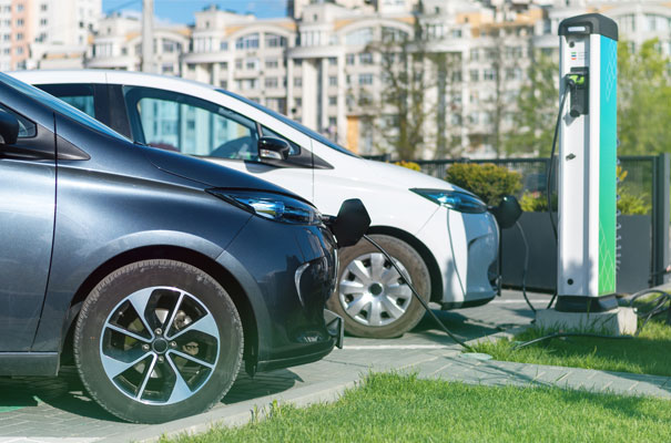 Electric Cars Charging at Public Station for Carbon Reduction. Two electric cars connected to charging station in urban environment.